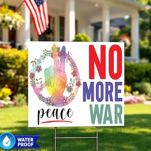 May include: A white yard sign with the words "NO MORE WAR" in red, purple, and green. The sign features a peace sign hand gesture in rainbow colors, surrounded by flowers, and the word "peace" in cursive.