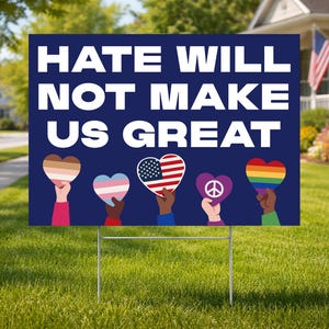 May include: A dark blue yard sign with the message "HATE WILL NOT MAKE US GREAT" in white. The sign features hands holding heart-shaped symbols with various designs, including the American flag and a rainbow.
