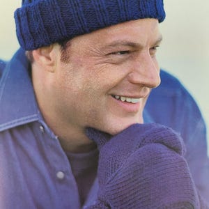 May include: A knitted blue beanie hat and matching gloves. The hat is a close-fitting style with a ribbed design. The gloves are also knitted in a matching blue colour. The person in the image is wearing a blue denim shirt.