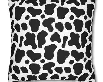 Può includere: Cuscino quadrato con un motivo a macchie di mucca in bianco e nero. Il cuscino presenta grandi macchie nere irregolari su sfondo bianco, creando un design audace e giocoso. Il cuscino ha una forma quadrata, perfetto per aggiungere un tocco di fantasia a qualsiasi stanza.