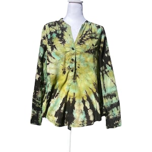 May include: A long-sleeved shirt with a tie-dye pattern in shades of green, yellow, and black. The shirt has a V-neck, two chest pockets, and a button-down front. The fabric appears to be lightweight.