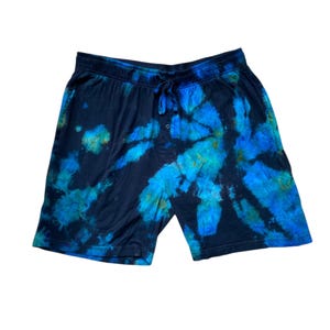 May include: Black and blue tie-dye shorts with a drawstring waist. The shorts have a button closure and a vibrant pattern of blue and teal hues against a dark background. Casual wear.