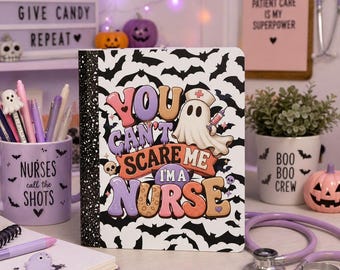 May include: A rectangular notebook featuring a white background with a black bat pattern. The center displays a cartoon ghost wearing a nurse cap and holding a syringe, with the text: You can't scare me I'm a nurse, in colorful, retro-style lettering.