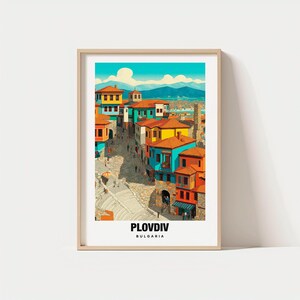 May include: A framed art print featuring a colorful illustration of Plovdiv, Bulgaria. The artwork depicts buildings with orange, yellow, and blue facades, a cobblestone street, and a bright blue sky. The text "PLOVIV" and "BULGARIA" are at the bottom.