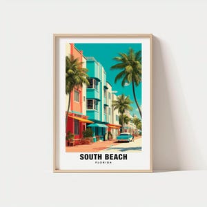 May include: A framed art print featuring a colorful street scene in South Beach, Florida. The buildings are painted in vibrant hues of coral, turquoise, and white, with palm trees lining the street. A vintage car is parked on the road. The text "SOUTH BEACH FLORIDA" is at the bottom.