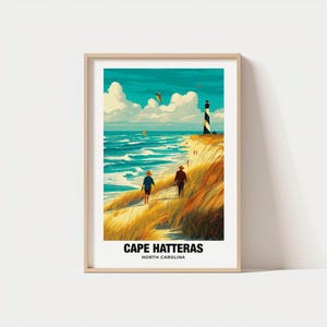 May include: Framed art print featuring a coastal scene with a lighthouse, beach, and two figures walking. The artwork has a vibrant color palette of blues, greens, and yellows. The text "CAPE HATTERAS NORTH CAROLINA" is displayed at the bottom.