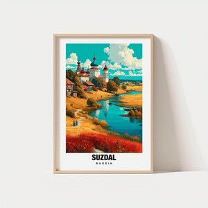 Puede incluir: Impresión artística enmarcada que presenta un vibrante paisaje de Suzdal, Rusia. La obra de arte representa un río que serpentea a través de un campo de hierbas rojas y amarillas, con edificios e iglesias bajo un cielo azul. La palabra "SUZDAL" está impresa en la parte inferior.