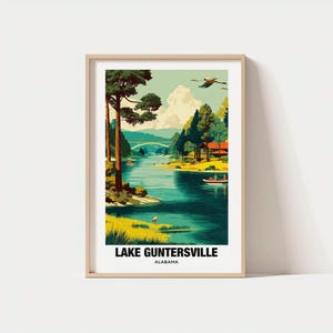 May include: A framed art print featuring a scenic view of Lake Guntersville, Alabama. The artwork depicts a serene lake scene with trees, boats, and a bridge. The color palette includes shades of green, blue, and yellow, with the text "LAKE GUNTERSVILLE ALABAMA" at the bottom.