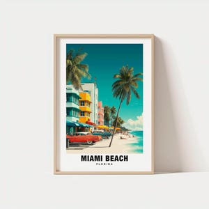 May include: Framed art print featuring a vibrant Miami Beach scene. The image showcases colorful Art Deco buildings, palm trees, classic cars, and a beach with people. The text "MIAMI BEACH FLORIDA" is displayed at the bottom of the print.