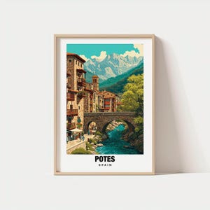 Puede incluir: Una impresión enmarcada de Potes, España, con un puente de piedra sobre un río, edificios y montañas en el fondo. La obra de arte tiene un estilo de cartel de viaje vintage, con un cielo turquesa y el texto "POTES SPAIN" en la parte inferior.