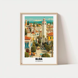 May include: A framed art print featuring a vibrant illustration of Blida, Algeria. The artwork depicts a cityscape with white buildings, red-tiled roofs, and a tall white minaret. The print includes the text "BLIDA ALGERIA" at the bottom.