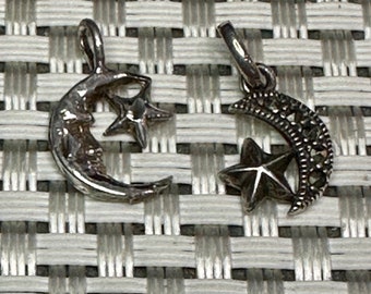 May include: Two silver charms in the shape of a crescent moon and a star. One charm has a smooth finish, while the other has a textured finish.