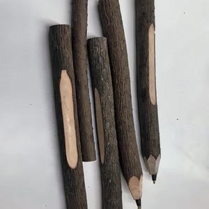 May include: Five brown wooden pencils with heart-shaped tips. The pencils are made from natural wood and have a light brown center.