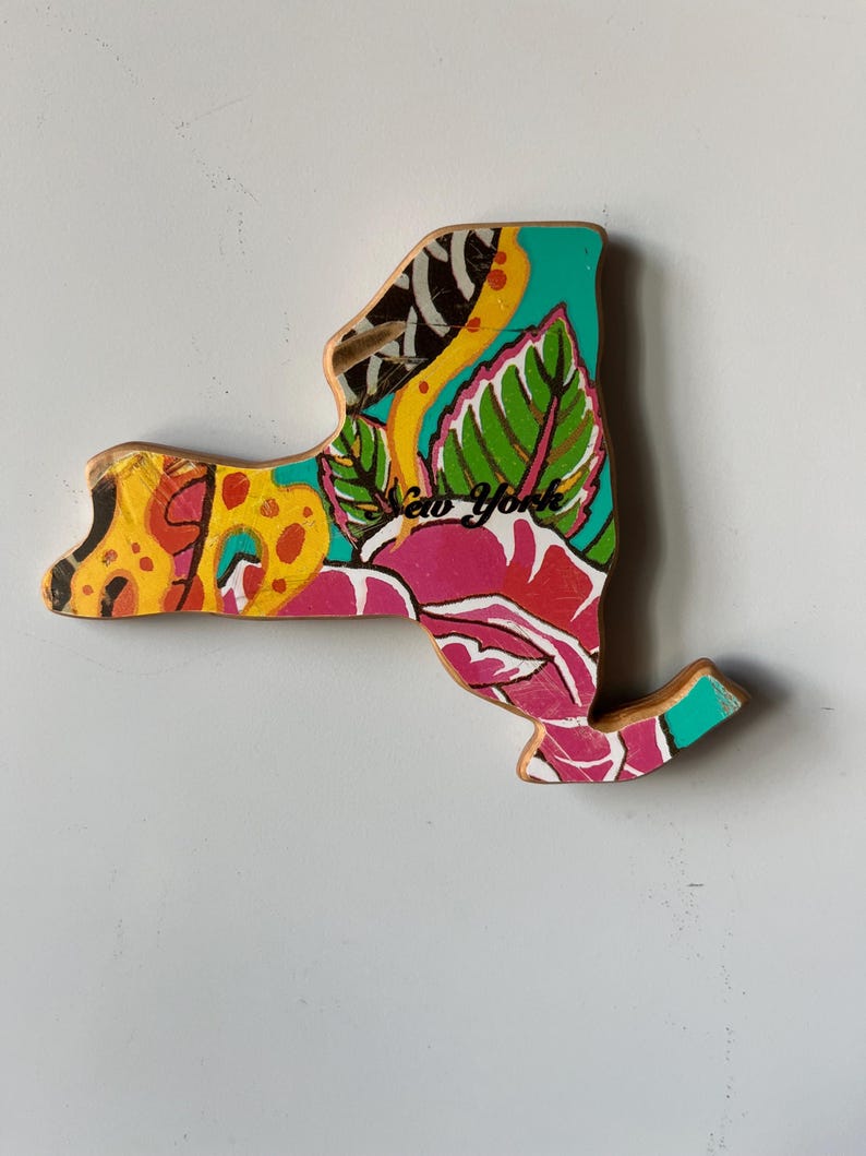 May include: Wooden New York state cutout with a colorful floral design. The artwork features a vibrant mix of pink, yellow, green, and teal, with the words "New York" written across the center.