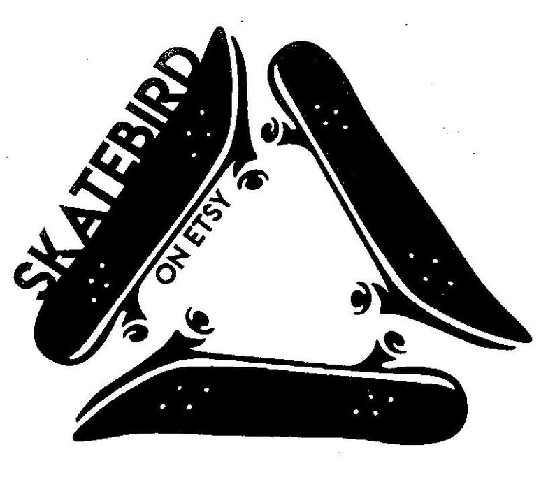May include: Black and white graphic of three skateboards arranged in a triangle. The word "SKATEBIRD" is printed on one skateboard, with "ON ETSY" below it. The skateboards have wheels and are set against a white background.