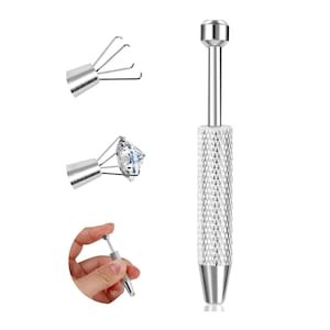 May include: A silver-toned metal prong holder tool featuring a knurled cylindrical handle and a spring-loaded plunger mechanism. The tool includes four thin wire prongs at the tip designed to extend and retract to securely grasp small gemstones.