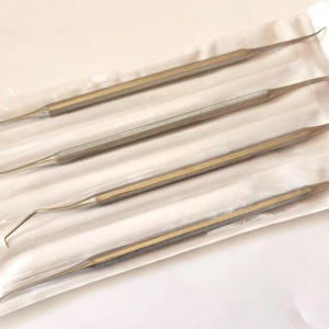 May include: Four stainless steel dental tools with curved ends, packaged in a clear plastic sleeve.