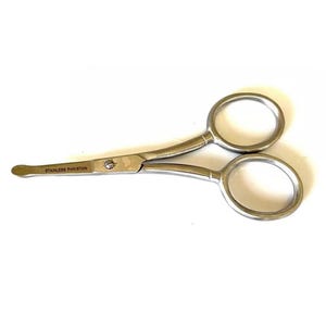 May include: Small, silver scissors with circular finger holes. The blades are curved, and the text "STAINLESS PAKISTAN" is visible. These scissors are designed for detailed cutting tasks. The overall design is compact and functional.