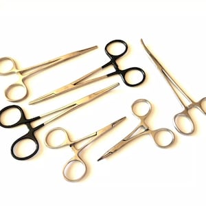 Puede incluir: Un juego de seis pinzas quirúrgicas, incluyendo un par con mangos negros. Las pinzas son de acero inoxidable y tienen una variedad de tamaños y formas.