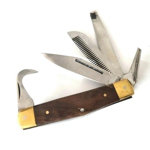 May include: A multi-tool knife with a dark wood handle and brass accents. The knife features several stainless steel blades, including a saw, a curved blade, and a pointed blade. The blades are open, displaying the tool's versatility.