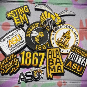 Peut inclure: Ensemble de patchs brodés aux couleurs jaune et noir. Les patchs affichent des textes tels que "#STING EM", "BUZZIN'", "ALABAMA STATE UNIVERSITY" et "STRAIGHT OUTTA ASU". Plusieurs patchs incluent une abeille.