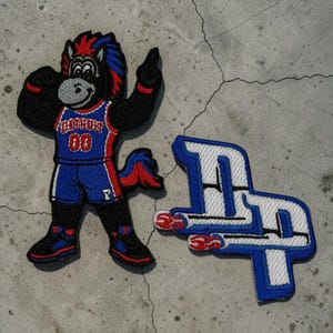 May include: Embroidered patches featuring a black horse mascot in a blue and red basketball uniform with the word "DETROIT" and the number "00". A second patch displays the letters "DP" in blue and white.