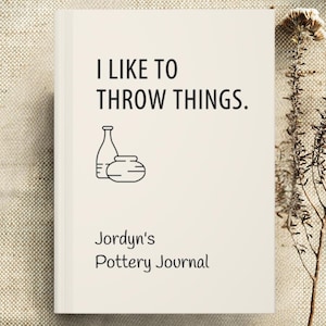 May include: A cream-colored journal with the text "I LIKE TO THROW THINGS." and an illustration of pottery. Below the text is "Jordyn's Pottery Journal."