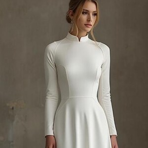 May include: A long-sleeved, white wedding dress with a high neckline and a flared skirt. The dress features a fitted bodice and a simple, elegant design. The dress is made of a smooth, opaque fabric.