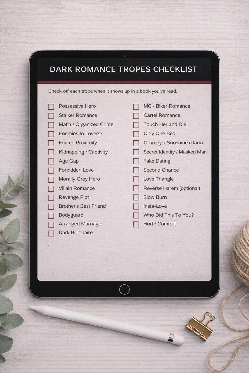 K&ouml;nnte beinhalten: Ein Tablet-Computer zeigt eine Checkliste mit dem Titel &bdquo;Dark Romance Tropes Checklist&ldquo;. Die Liste enth&auml;lt Roman-Tropen wie &bdquo;Besitzergreifender Held&ldquo;, &bdquo;Mafia&ldquo; und &bdquo;Arrangierte Ehe&ldquo;. Ein Stift, eine goldene B&uuml;roklammer und ein Garnkn&auml;uel liegen auf dem Tisch.
