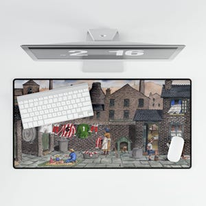 May include: A rectangular mouse pad featuring a detailed illustration of a brick village scene with people, buildings, and laundry hanging on a clothesline. A white keyboard and mouse are on the pad.