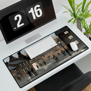 May include: A rectangular desk mouse pad featuring a vintage street scene with figures and buildings in shades of brown, gray, and beige. A white keyboard and mouse are on the pad. A computer monitor and plant are in the background.