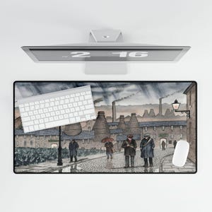 Könnte beinhalten: Rechteckige Schreibtischunterlage mit einem Aquarellgemälde einer historischen Industrieszene mit Figuren, die auf einer Kopfsteinpflasterstraße gehen. Eine weiße Tastatur und Maus liegen auf der Unterlage. Ein Computermonitor befindet sich darüber.