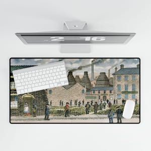 May include: A rectangular desk mat featuring a detailed watercolor painting of a historical industrial scene with buildings, people, and smokestacks. A white keyboard and mouse are on the mat. The monitor above displays the numbers "2 16".