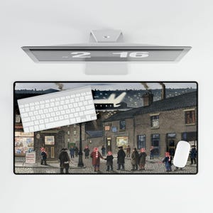 May include: A rectangular mouse pad featuring a detailed painting of a street scene with people wearing red and white striped hats and scarves. A white keyboard and mouse are on the pad. The monitor above displays the time.