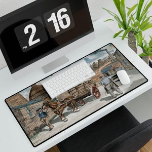 May include: A rectangular desk mouse pad featuring a historical painting of a horse-drawn cart and two men. The pad is black-edged and sits on a white desk with a computer, keyboard, and mouse.