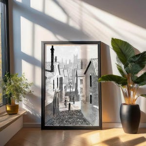 Puede incluir: Una ilustración en blanco y negro de una calle estrecha en una ciudad con edificios a cada lado. La calle está adoquinada y hay dos personas caminando por la calle. Los edificios son de diferentes alturas y tienen ventanas y puertas. El cielo está nublado.