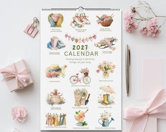 May include: A 2027 wall calendar featuring watercolor illustrations of seasonal items like ice skates, a bicycle, flowers, and gardening tools. The text reads 2027 CALENDAR Finding beauty in the little things, all year long, along with various short phrases under each small illustration.