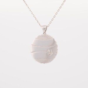 May include: Silver pendant necklace with a circular design featuring a textured surface and a small bee design in the center.