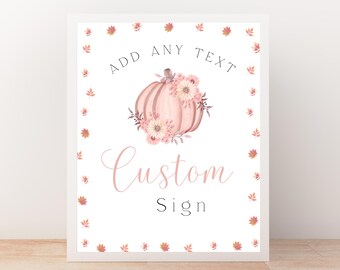 May include: A framed custom sign with a watercolor design. The sign features a pink pumpkin adorned with flowers, the words "ADD ANY TEXT" above the pumpkin, and "Custom Sign" below. The border is decorated with small leaves.