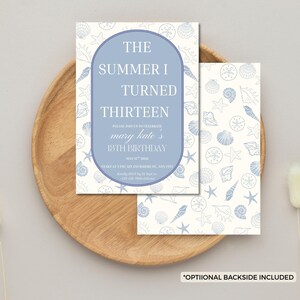 Pode incluir: Um convite azul claro e branco com o texto "THE SUMMER I TURNED THIRTEEN" e "mary kate's 13TH BIRTHDAY". O convite tem um padr&atilde;o de conchas e est&aacute; em uma bandeja de madeira.