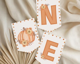 May include: A set of autumn-themed bunting with the letters "N" and "E", and a pumpkin illustration. The letters are in a warm orange colour, and the edges are decorated with small floral and leaf accents. The pumpkin is adorned with flowers.