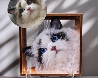 Op de afbeelding: Een wit-zwarte kat met blauwe ogen is ingelijst in een gouden lijst. De kat kijkt omhoog en naar rechts. De lijst staat op een heldere acryl standaard.