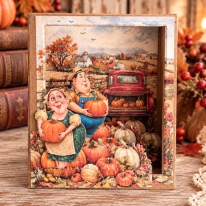 May include: A three-dimensional shadow box featuring a layered illustration of a person in a green dress and a person in blue overalls holding pumpkins. A red pickup truck sits in a field with orange trees, a farmhouse, and numerous pumpkins.