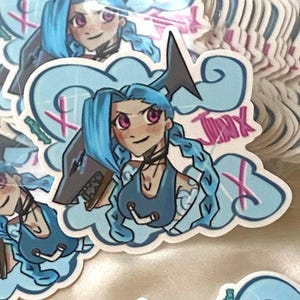 May include: A sticker featuring a cartoon character with blue hair and a shark fin. The character is wearing a blue top and has a pink and white X behind her. The sticker says "Jinx" in pink letters.