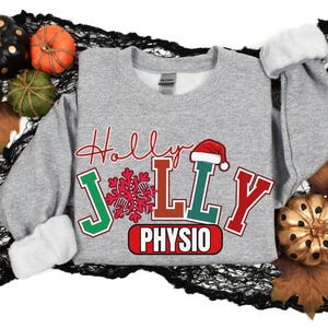 May include: A grey sweatshirt featuring the text "Holly Jolly Physio" in red, green, and white, with a Santa hat above "Jolly". The image includes decorative pumpkins and autumn leaves.