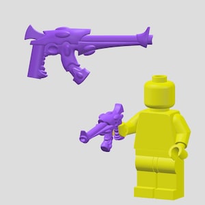 Puede incluir: Una minifigura Lego amarilla sosteniendo una pistola de juguete de plástico púrpura. La pistola tiene un diseño futurista con un cañón largo y un mango con un gatillo.