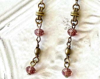 May include: A pair of long, dangling earrings with a chain of brass-colored metal links and small, faceted, pink glass beads.