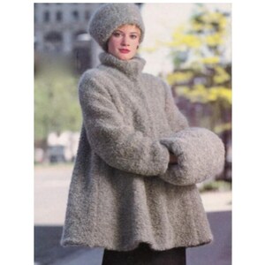 May include: A gray, textured coat with a matching hat and mittens. The coat has a high collar and a flared shape. The hat is a close-fitting style. The mittens are large and puffy. The outfit is made of a soft, fuzzy material.
