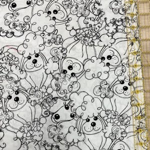 May include: A white fabric featuring a repeating black line art pattern of curly-haired dogs. A yellow plastic ruler is positioned along the right edge, showing measurements in centimetres from 1 to 40 cm, indicating the scale of the print.