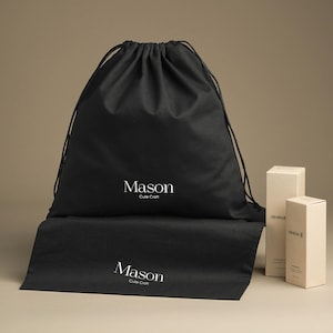 Könnte beinhalten: Schwarze Kordelzugtasche mit dem aufgedruckten Text "Mason Cute Craft". Die Tasche liegt auf einem Tisch mit zwei weißen Schachteln.